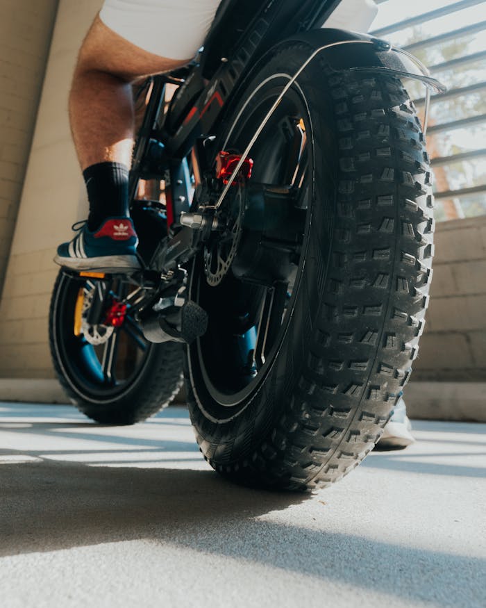 Dynamic low angle view of a person riding a bike in an urban environment, highlighting the tire and motion.